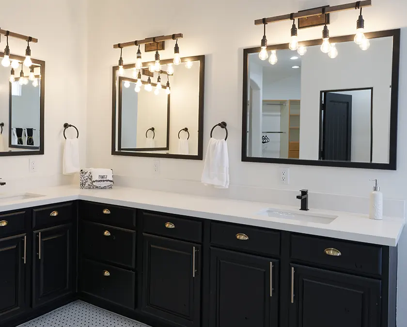 A bathroom with lighting above square mirrors and a large dark vanity