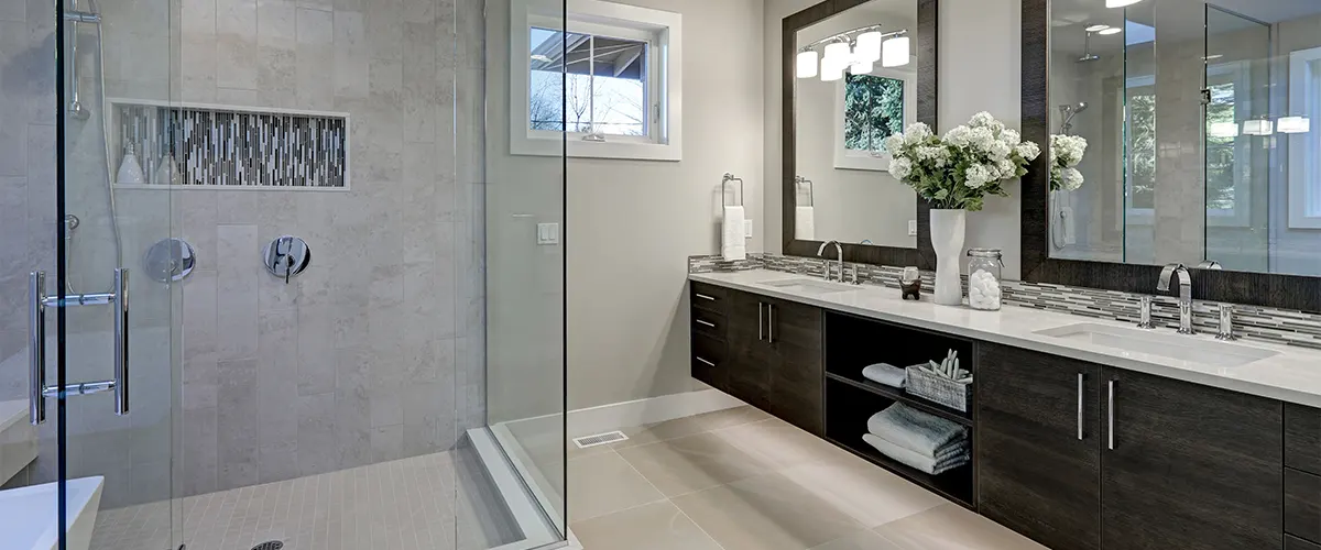 A glass walk-in shower with modern dark cabinets