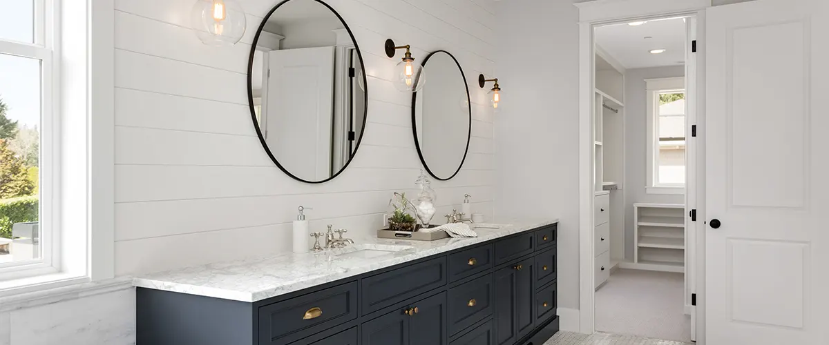 A double black vanity with two round mirrors and yellow lights