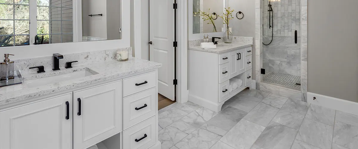 Two vanities with black hardware separated by a door