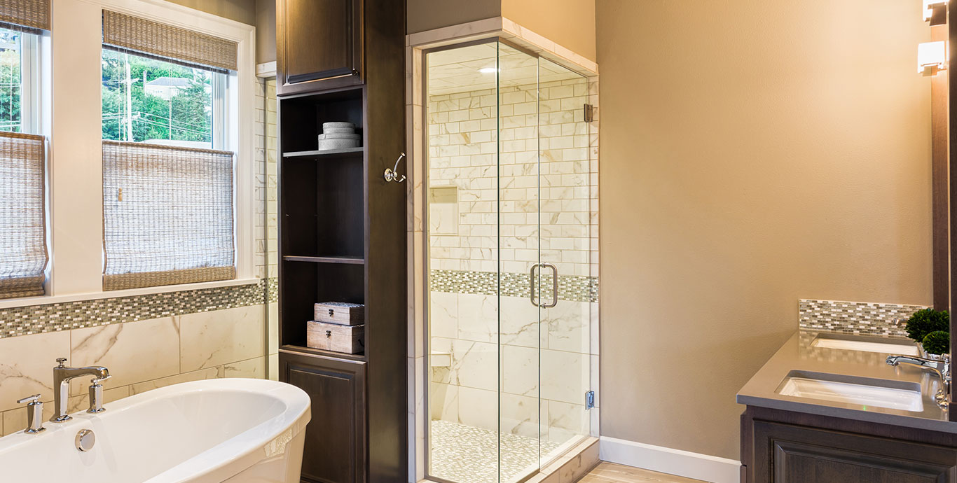 A glass shower and a wood cabinet with towels