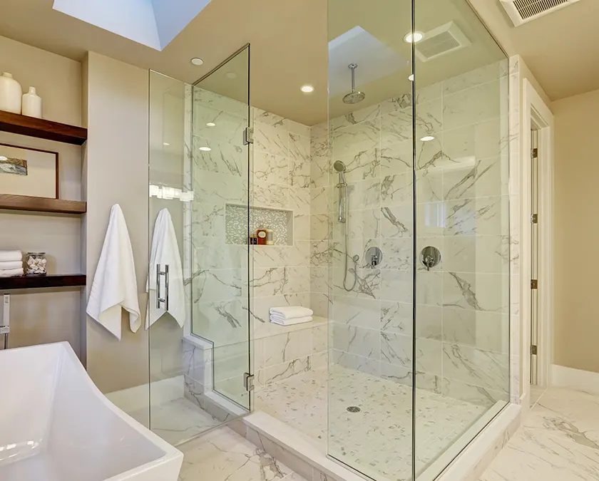 A glass shower with marble surround