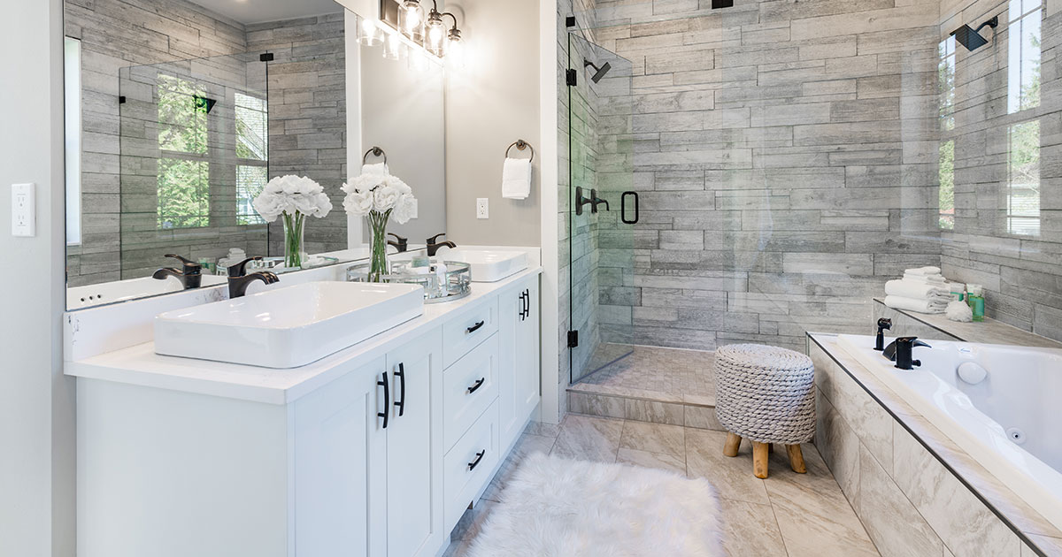 A bathroom with white vanity and black hardware, a walk-in shower with glass, and a white tub