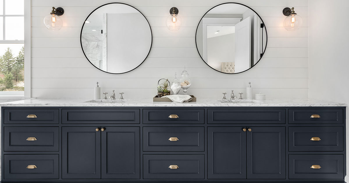 Dark blue double vanity with two round mirrors and sconces