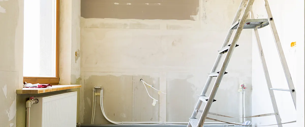 A ladder in an empty room with white walls in progress