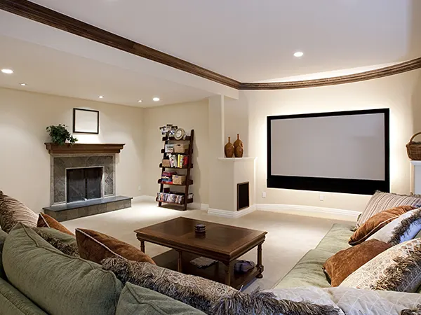 A big screen in a basement addition with a couch and small table