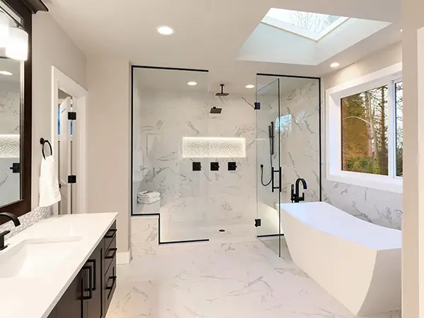 A bathroom with a glass shower with dark hardware and a tub with a dark faucet
