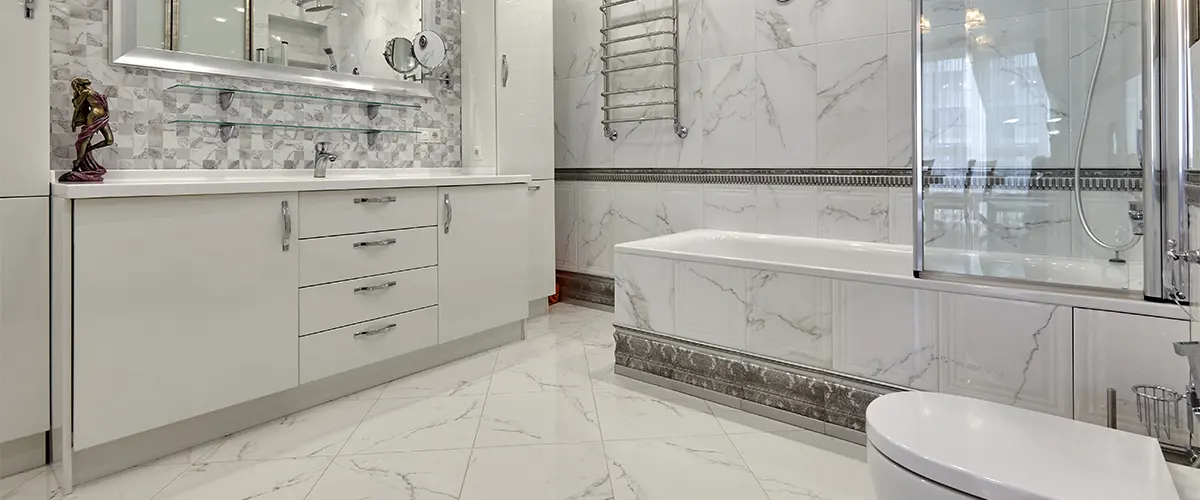 A modern white bathroom with laminate cabinets and glass shower