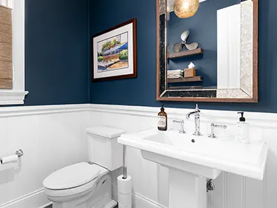 A powder room with dark blue walls and a painting