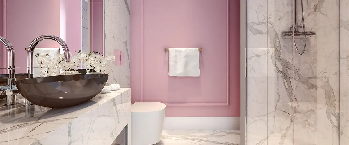 A bathroom with pink walls and a dark vessel sink