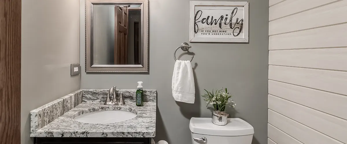 A small bathroom with dark accents and a small quote on the wall