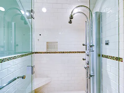 A glass shower with two shower heads and tile surround