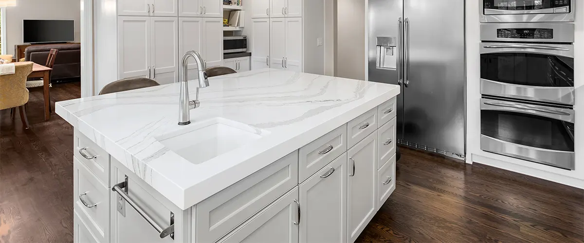A white island with marble countertop material and gray fridge