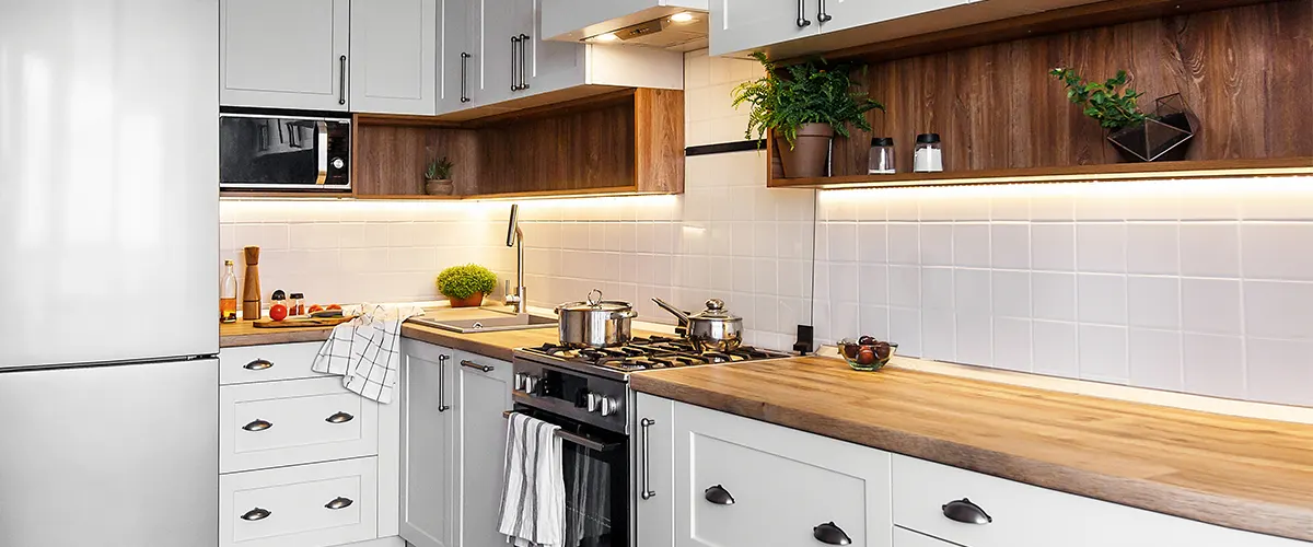 A wooden countertop with plants and white cabinets