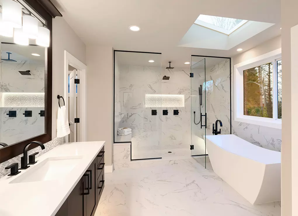 A bathroom with glass shower and dark hardware