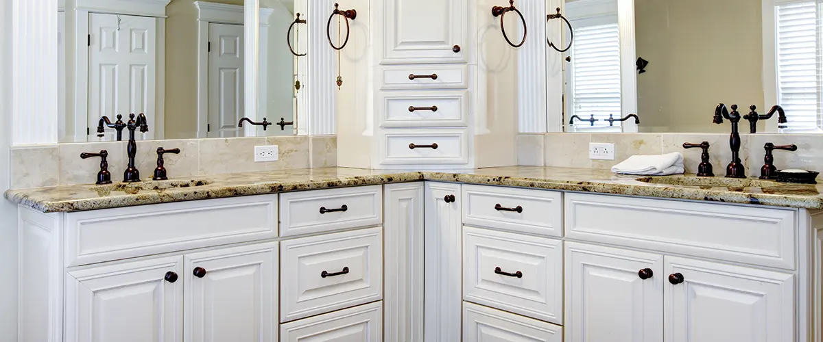 A double vanity with white doors and dark hardware with a quartz countertop