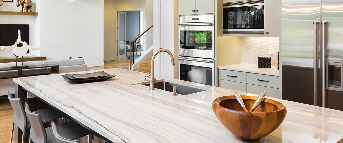 A quartz countertop with an undermount sink and a wooden bowl