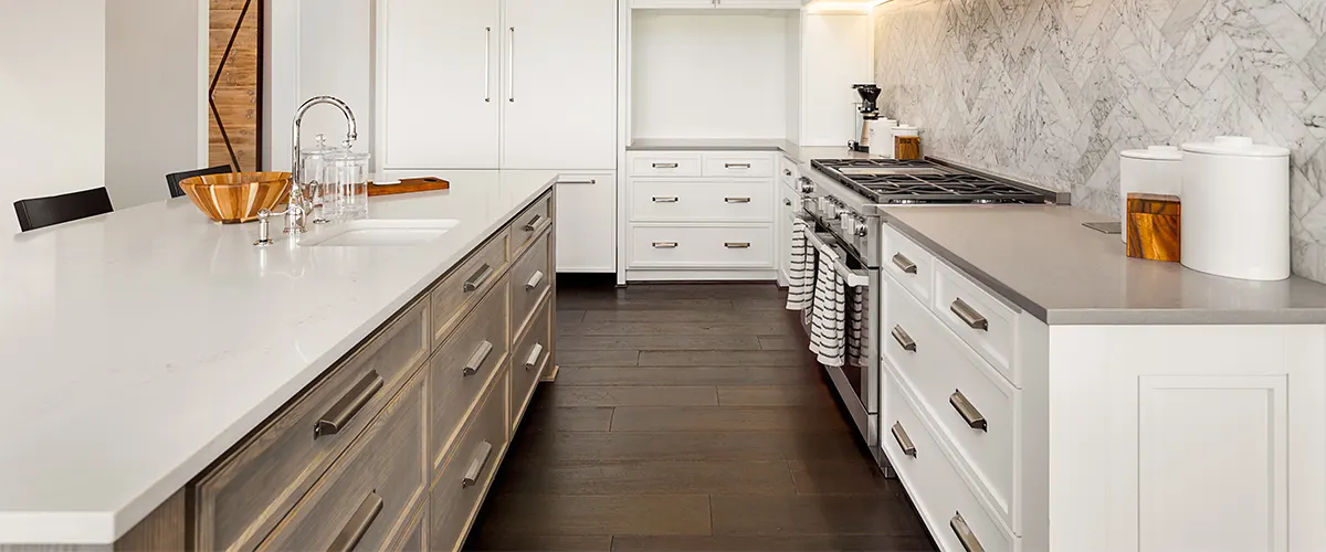 White cabinets in a kitchen with wood flooring and marble countertops