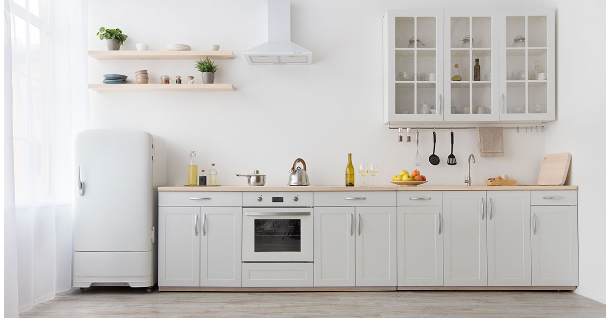 A white kitchen with silver hardware on cabinets and a vintage refrigerator
