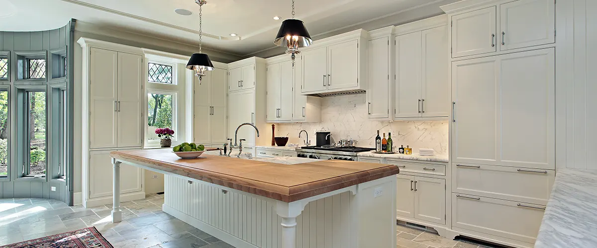 White cabinets in a large kitchen with an island and pendant lights