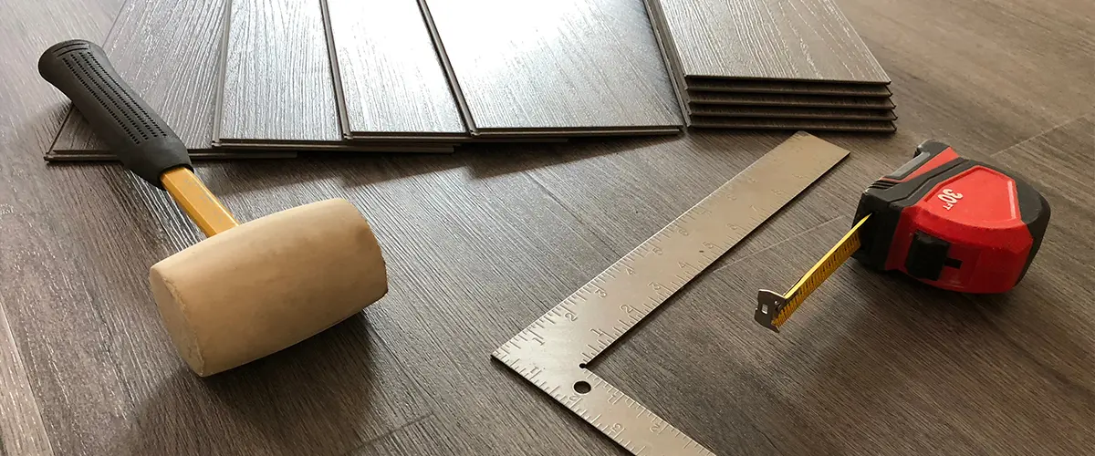 Luxury vinyl plank installation with a wood mallet and ruler