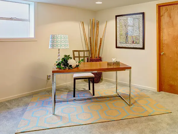 A simple desk on a carpet and a painting