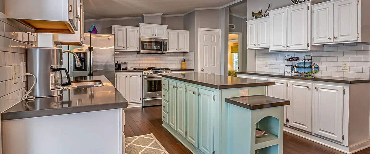 A large kitchen with white cabinets and a light green island