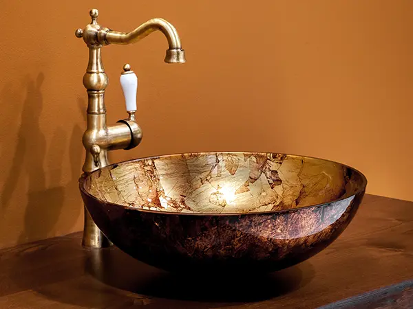 A copper sink with a golden water fixture