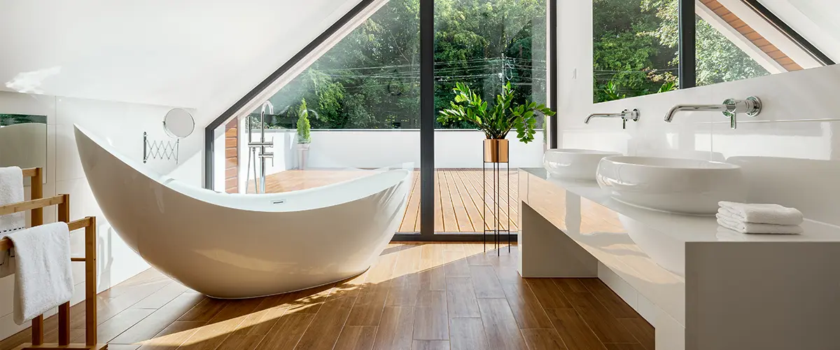 A bathroom with a freestanding tub and wood floor on a second floor bath