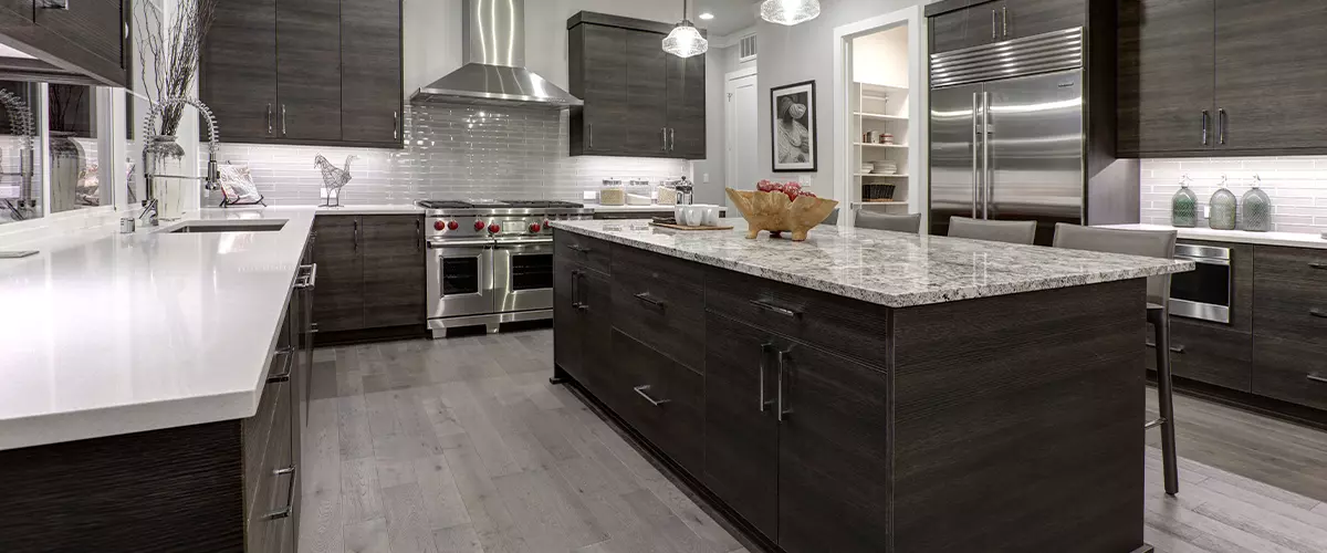 Modern gray kitchen island features dark gray flat front cabinets paired with white quartz countertops and a glossy gray linear tile backsplash